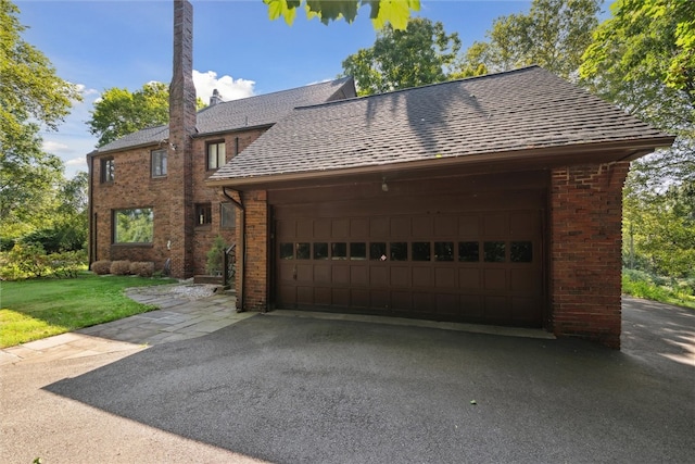 view of front facade featuring a garage, a front yard, brick siding, and a shingled roof