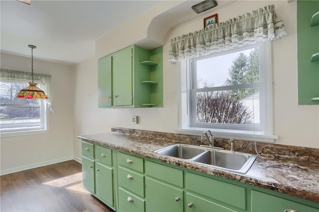 kitchen with open shelves, dark countertops, green cabinets, and a sink