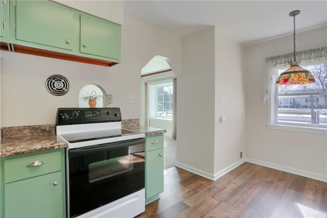 kitchen featuring baseboards, arched walkways, electric range oven, light wood-style floors, and green cabinets