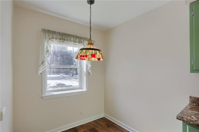 unfurnished dining area featuring baseboards and dark wood-type flooring