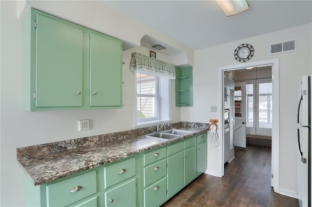 kitchen with dark countertops, visible vents, green cabinets, and a sink