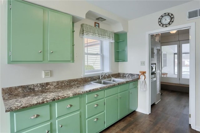 kitchen with dark countertops, a sink, and green cabinets