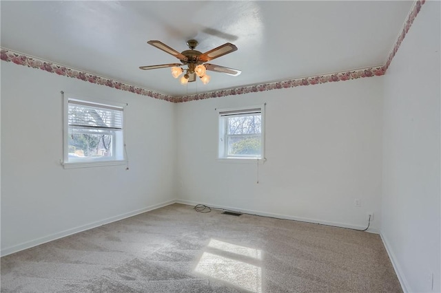 unfurnished room featuring visible vents, light colored carpet, a ceiling fan, and baseboards