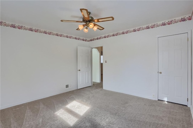 empty room with light colored carpet, visible vents, and ceiling fan