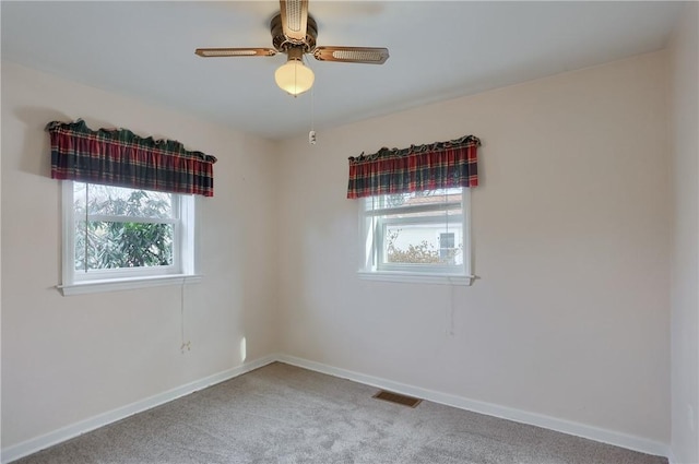 empty room featuring a ceiling fan, carpet, visible vents, and baseboards