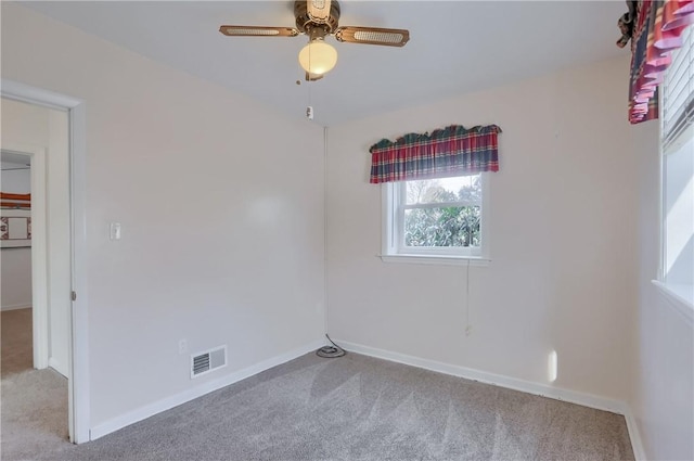 empty room featuring light carpet, baseboards, visible vents, and ceiling fan