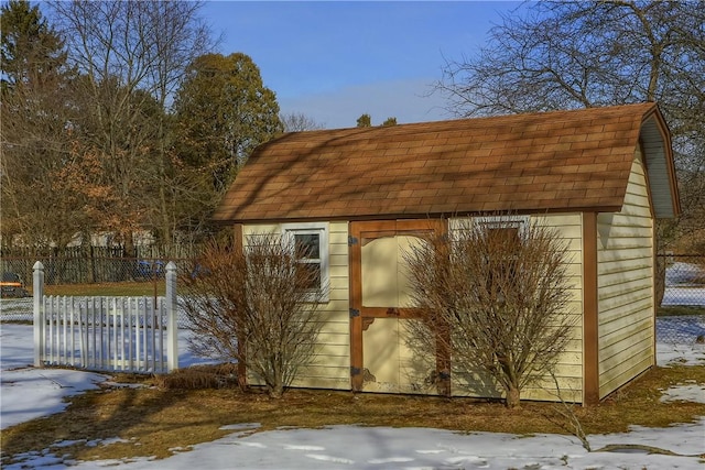 snow covered structure featuring a shed, fence, and an outdoor structure