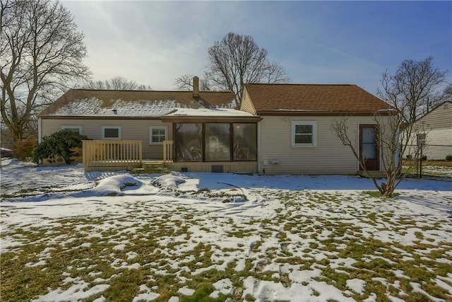 snow covered house with a sunroom and a deck