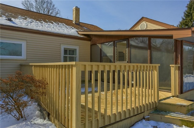 snow covered deck featuring a sunroom