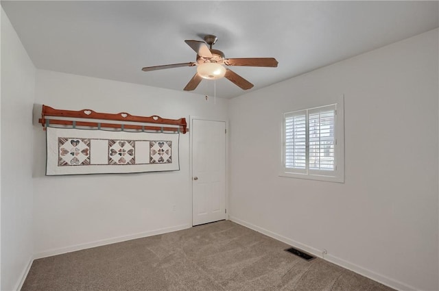 carpeted spare room with visible vents, baseboards, and ceiling fan