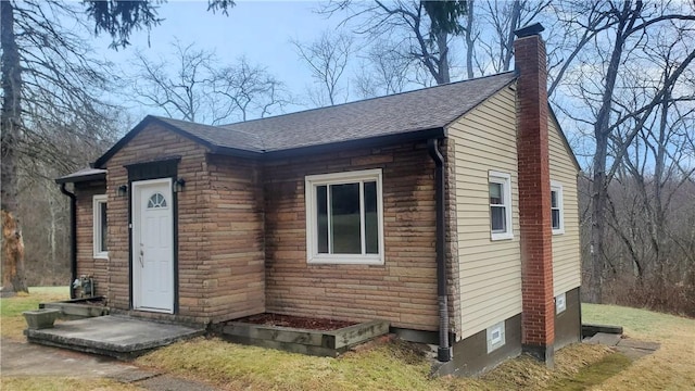 view of front of property featuring a chimney and roof with shingles