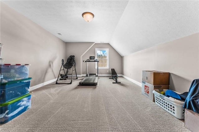 exercise room with a textured ceiling, vaulted ceiling, visible vents, and baseboards