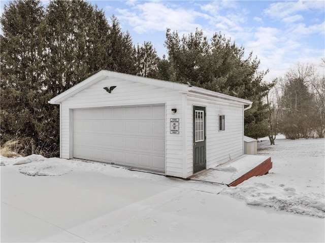 snow covered garage featuring a detached garage