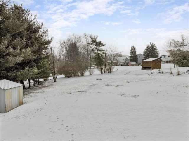 yard layered in snow with a garage, a shed, and an outdoor structure