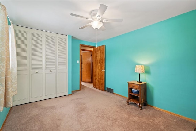 unfurnished bedroom featuring light carpet, a closet, a ceiling fan, and baseboards