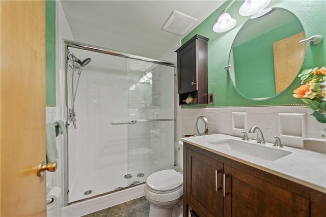 full bath featuring visible vents, toilet, vanity, a shower stall, and tile walls