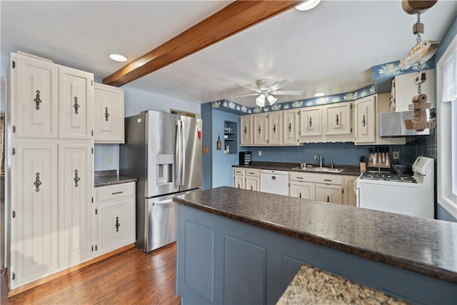 kitchen featuring dark countertops, dark wood-type flooring, white cabinets, a sink, and white appliances