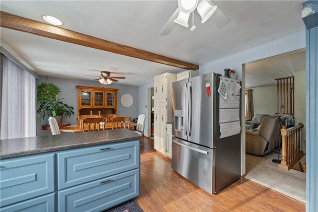 kitchen featuring stainless steel refrigerator with ice dispenser, dark countertops, open floor plan, ceiling fan, and wood finished floors