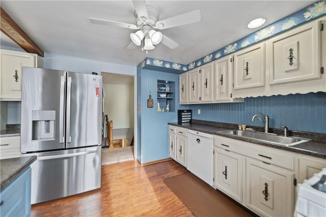 kitchen with dark countertops, white cabinets, stainless steel refrigerator with ice dispenser, and a sink