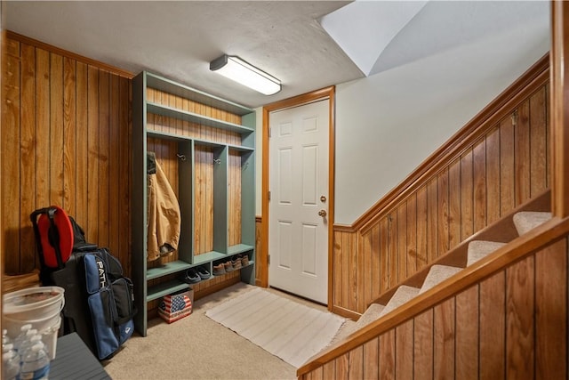 mudroom featuring light carpet and wood walls