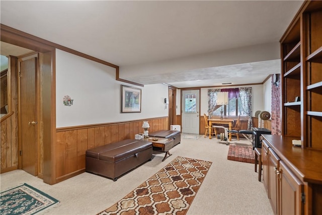 living area featuring light carpet, wood walls, crown molding, and wainscoting