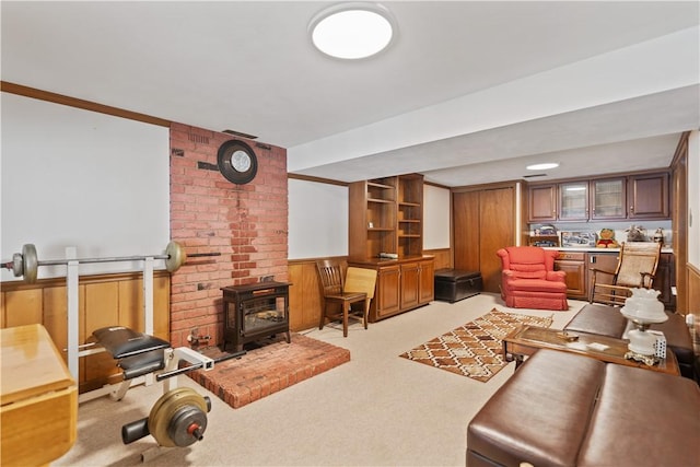 living area featuring a wood stove, wood walls, light carpet, and wainscoting