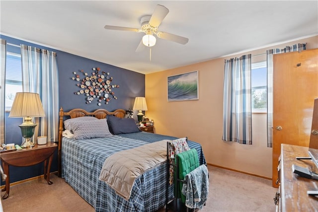 bedroom featuring light carpet, a ceiling fan, and baseboards