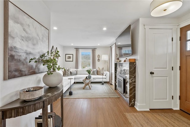 living room featuring light wood finished floors, recessed lighting, and a glass covered fireplace