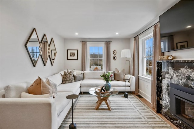 living area featuring recessed lighting, wood finished floors, a high end fireplace, and baseboards