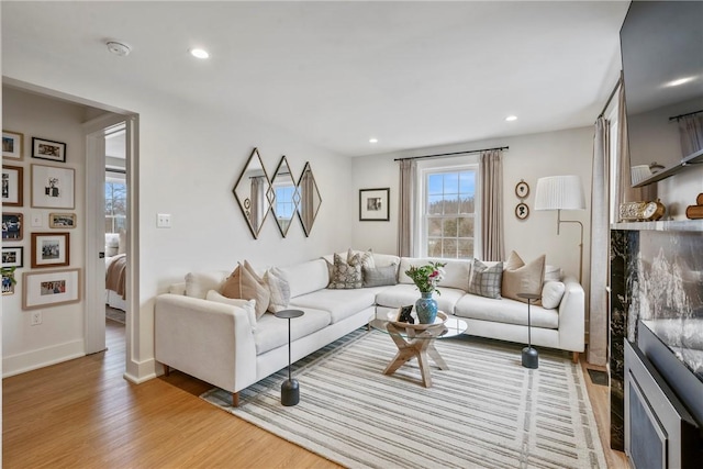 living room featuring baseboards, light wood finished floors, and recessed lighting