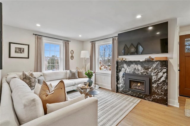 living area with a wealth of natural light, recessed lighting, wood finished floors, and a high end fireplace