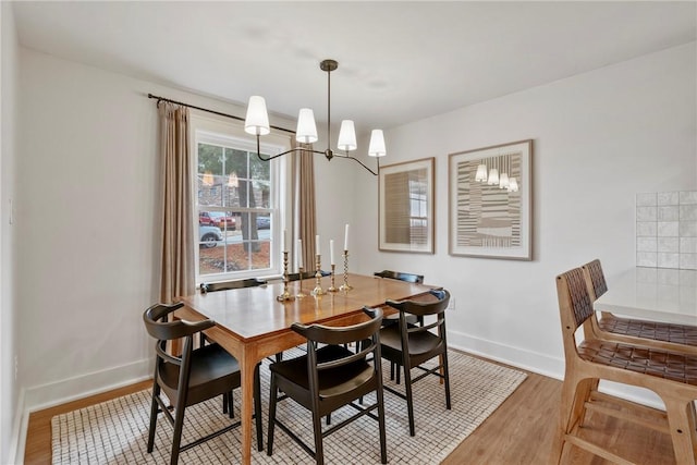 dining room featuring baseboards, a chandelier, and wood finished floors