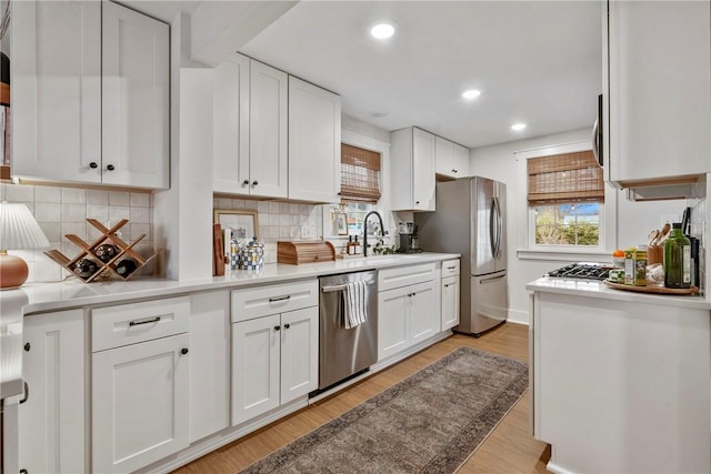 kitchen with stainless steel appliances, light countertops, a sink, and white cabinetry