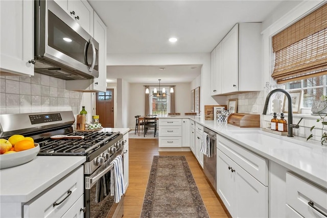 kitchen with stainless steel appliances, light countertops, and white cabinetry