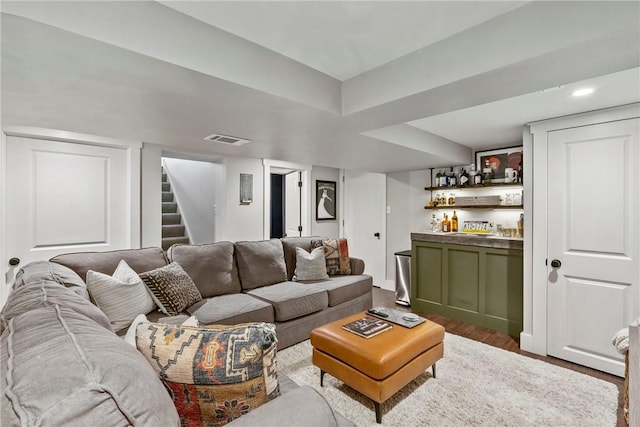 living room with a bar, stairs, visible vents, and wood finished floors