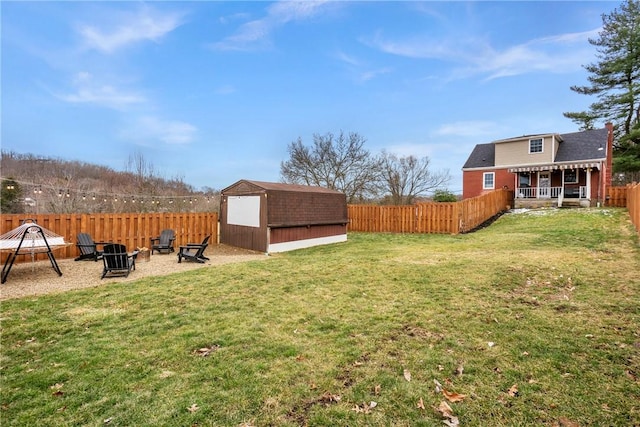 view of yard with a shed, a fire pit, a fenced backyard, and an outdoor structure