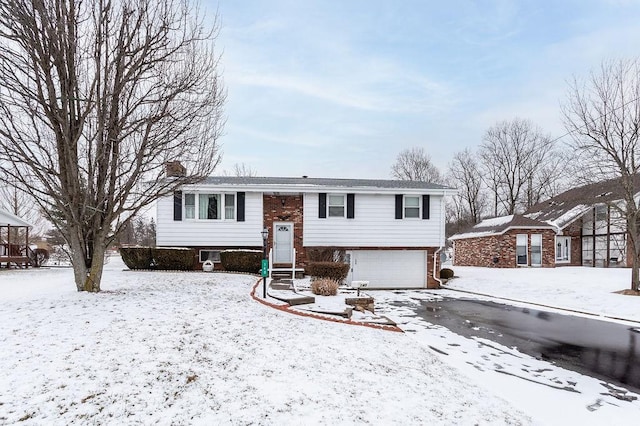 split foyer home featuring a garage, a chimney, and brick siding