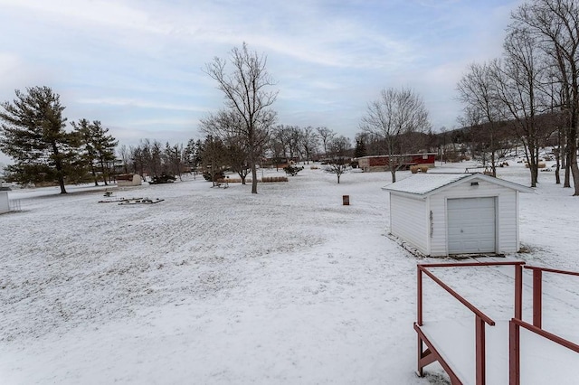 snowy yard featuring a garage and an outdoor structure