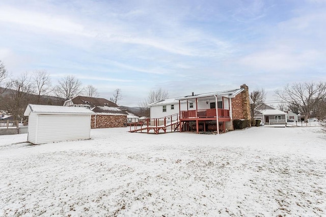 snow covered house featuring a detached garage and a chimney