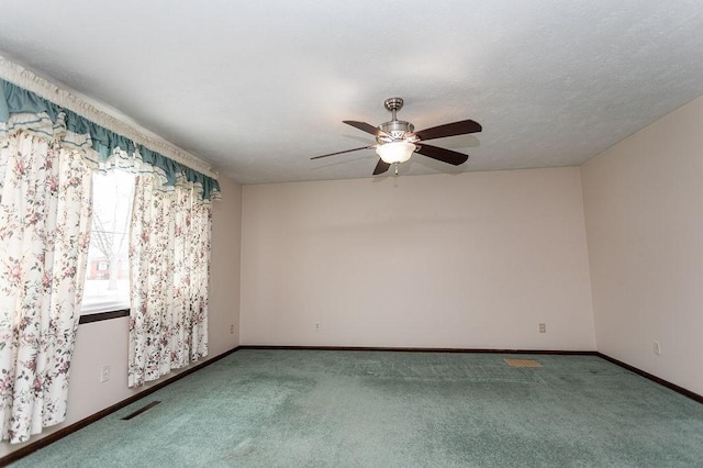 carpeted empty room with a ceiling fan, visible vents, and baseboards