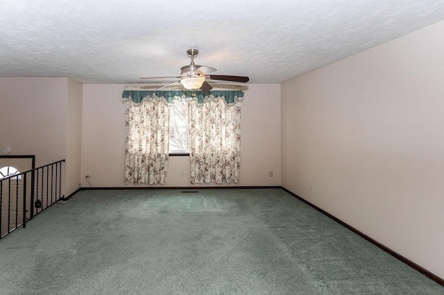 carpeted spare room featuring a textured ceiling, ceiling fan, and baseboards