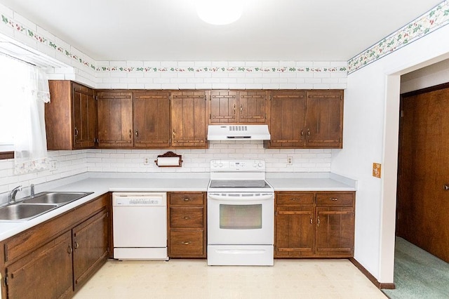 kitchen with white appliances, under cabinet range hood, light countertops, and a sink