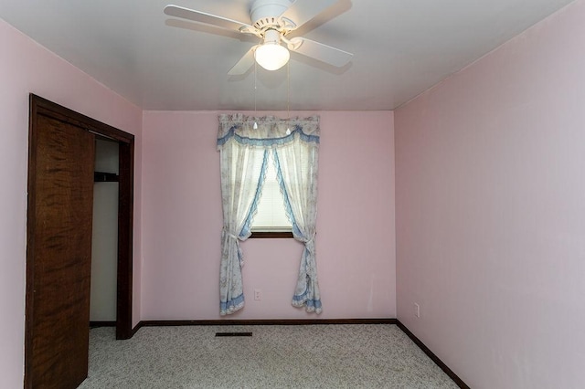 empty room with baseboards, ceiling fan, visible vents, and light colored carpet