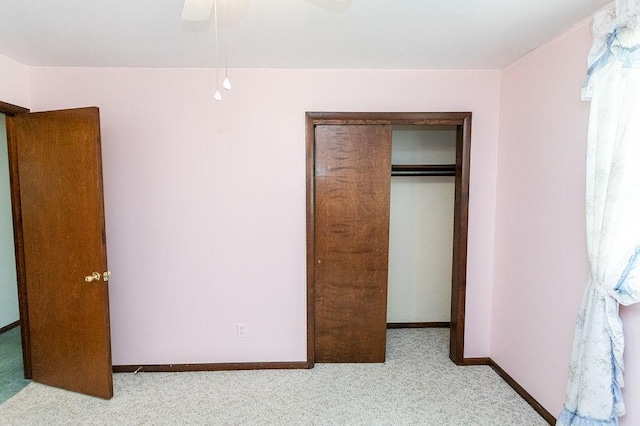 unfurnished bedroom featuring a closet, light carpet, ceiling fan, and baseboards