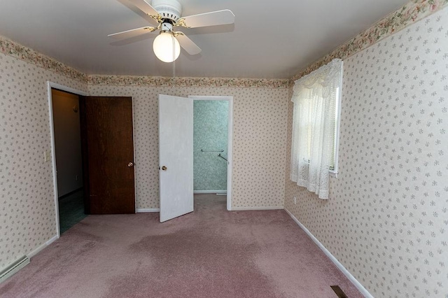 carpeted spare room featuring a baseboard heating unit, ceiling fan, baseboards, and wallpapered walls