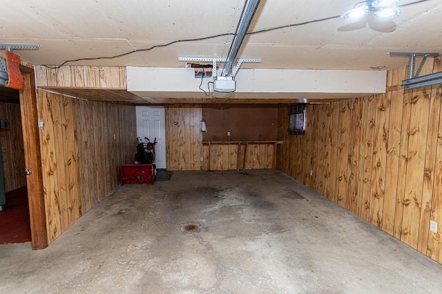 basement featuring a garage and wood walls