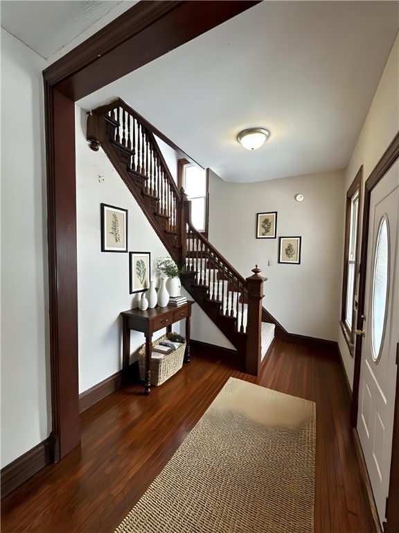 entrance foyer with dark wood-style floors, stairway, and baseboards