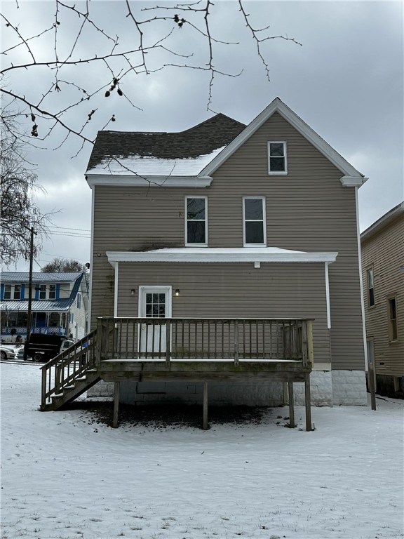 snow covered back of property featuring a deck