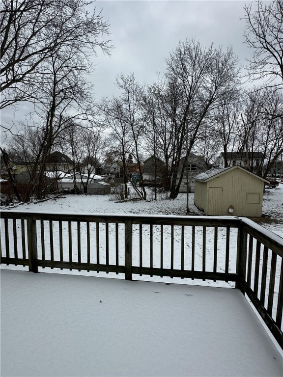 snow covered deck featuring a shed and an outbuilding