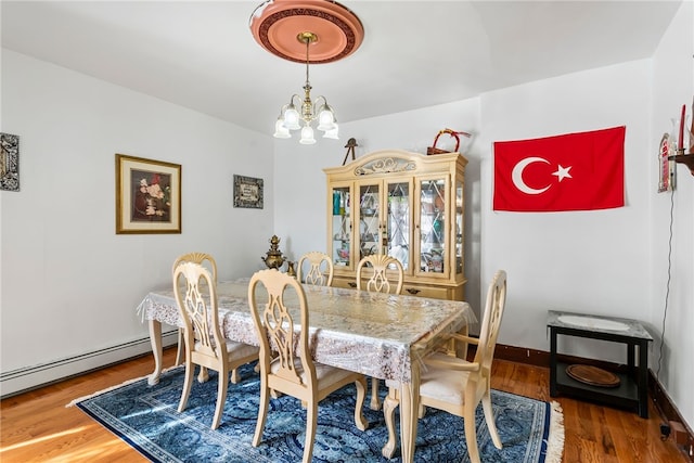 dining room featuring baseboards, a baseboard radiator, wood finished floors, and a notable chandelier